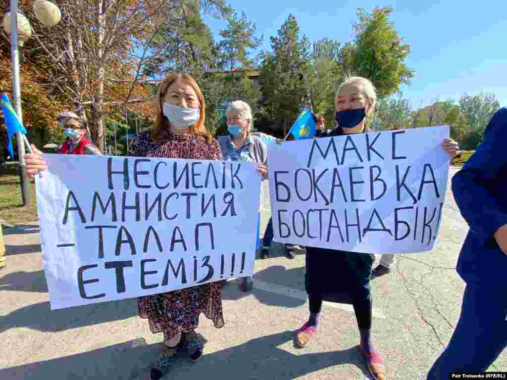 Алматыдағы наразылық акциясында несие амнистиясын жариялау, саяси тұтқындарды босату туралы талап жазылған плакат ұстап тұрған адамдар.