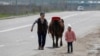 KAZAKHSTAN -- A woman and a child walk with a cow along a street during a lockdown imposed by the government as part of state of emergency to prevent the spread of the coronavirus disease (COVID-19) in Almaty, April 14, 2020