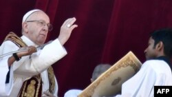 Pope Francis (L) blesses the faithful from the balcony of St Peter's basilica 