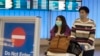 (FILES) In this file photo taken on January 22, 2020 passengers wear protective masks to protect against the spread of the Coronavirus as they arrive at the Los Angeles International Airport, California.